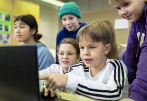 Oppijoita luokassa työskentelemässä yhdessä tietokoneella.