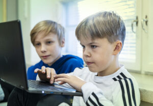 Kaksi poikaa opiskelee tietokoneen ääressä